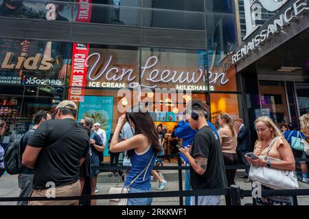 Hunderte von Eisliebhabern warten am Donnerstag, den 24. August 2023, auf die Eröffnung des 50. Van Leeuwen Eisdielen-Ladens am Times Square in New York. Die Marke hat sich mit dem berühmten Küchenchef Jean-Georges Vongerichten zusammengetan, um eine Sonderedition mit dem Geschmack „Sour Cherry Creamsicle“ zu kreieren. (© Richard B. Levine) Stockfoto