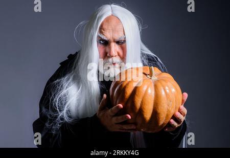 Teufelsvampirmann mit Halloween-Kürbis. Horror. Männlicher Dämon mit Jack-o-Laterne. Zauberer hexer alter Mann. Teufelsmann mit Kürbis an Halloween Nacht Stockfoto