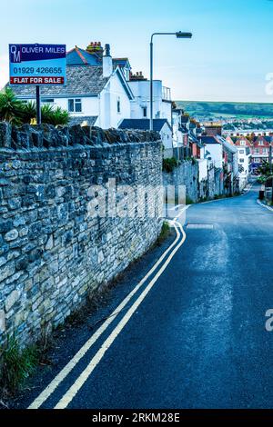 Zum Verkauf und eine Reihe britischer Reihenhäuser in Swanage, einer Küstenstadt in Großbritannien. Britischer Wohnungsmarkt. Immobilienmarkt. Hypotheken. Konzept. Zusammenfassung. Stockfoto