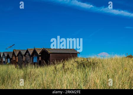 Typisch britische Strandhütten in Studland Bay, Dorset, im Sommer. Blauer Himmel, grünes Gras und Sanddünen. Urlaub, Urlaub. Vermietungen. Stockfoto