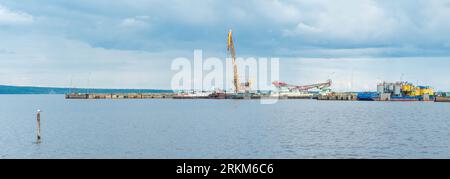 Panorama des Frachtpiers mit Kränen und technischen Schiffen an regnerischen Tagen Stockfoto