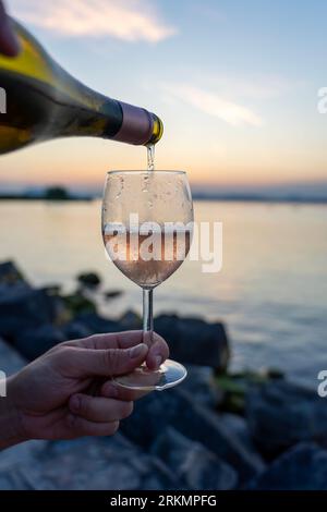 Gießen Sie Wein in ein Glas aus einer Flasche auf ein Picknick am Plattensee. Stockfoto