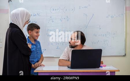 Mutter, die mit dem Lehrer in der Schule über den akademischen Fortschritt des Sohnes spricht Stockfoto