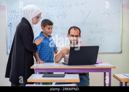 Mutter, die mit dem Lehrer in der Schule über den akademischen Fortschritt des Sohnes spricht Stockfoto