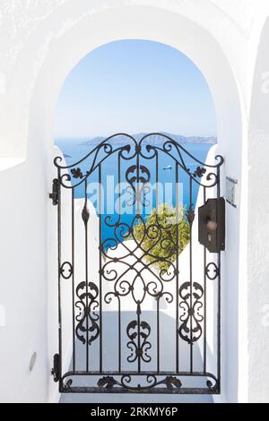 Traumhafter Blick auf Caldera durch eine alte traditionelle Eisentür auf Santorin in Griechenland, einem der schönsten Reiseziele der Welt. Stockfoto