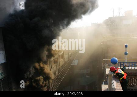 Bildnummer: 57043508  Datum: 09.02.2012  Copyright: imago/Xinhua (120209) -- LAHORE, Feb. 9, 2012 (Xinhua) -- A rescuer looks down to the street as smoke rises from the fire site in eastern Pakistan s Lahore on Feb. 9, 2012. At least 6 were hurt and some 30 shops were burnt as a commercial market caught fire in Lahore on Thursday. Chief Fire Officer told the media that thirteen water tankers took part in the fire extinguishing operation, whereas 30 shops turned to ashes by the time when the fire came under control. (Xinhua/Jamil Ahmed) (msq) PAKISTAN-LAHORE-FIRE PUBLICATIONxNOTxINxCHN Gesellsc Stock Photo