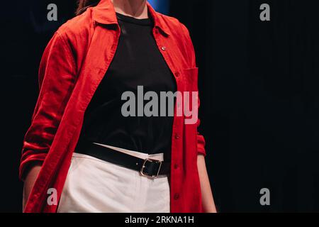 Elegante weiße Hose, schwarzes Oberteil und rotes Hemd mit Knöpfen auf dem weiblichen Körper. Modische Details. Stil, Design von Damenbekleidung und Accessoires. Stockfoto