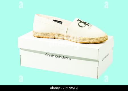 Nahaufnahme der Box mit Calvin Klein Espadrilles Sandalen isoliert auf blauem Hintergrund. Stockfoto