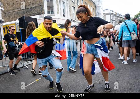 London, UK. 29th Aug, 2022. Two spectators wearing two different flags are seen dancing during the event. After 2 years of pandemic, the biggest street party in Europe, Notting Hill Carnival returned in 2022, being the 54th carnival since 1966. It is expected that there are 2 million attendees at Carnival plus 40,000 volunteers and 9,000 police. (Credit Image: © Daniel Lai/SOPA Images via ZUMA Press Wire) EDITORIAL USAGE ONLY! Not for Commercial USAGE! Stock Photo