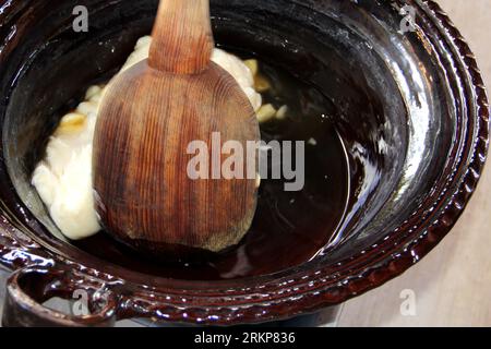 Erster Schritt bei der Zubereitung des traditionellen mexikanischen Maulwurfgerichts in einem Tontopf. Die Zutaten sind Butter und Knoblauch, die im Ofen gekocht und gemischt werden Stockfoto