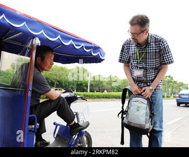 Bildnummer: 58021960 Datum: 07.05.2012 Copyright: imago/Xinhua (120522) -- SHANGHAI, 22. Mai 2012 (Xinhua) -- Anatoly Burov (R) erkundigt sich bei einem Motorradfahrer nach dem Preis in Shanghai, Ostchina, 7. Mai 2012. Der 39-jährige Anatoly Burov kommt aus St. Petersburg. Nach seinem Abschluss am Rochester Institute of Technology im Jahr 2008 gründete er mit seinem Tutor in den Vereinigten Staaten ein Unternehmen für elektronische Technologie. Um Geschäfte mit dem Kunden des Unternehmens zu verhandeln, kam Anatoly im selben Jahr zum ersten Mal nach Shanghai. Diese Kurzzeit-Erfahrung machte ihn begeistert von Port c Stockfoto