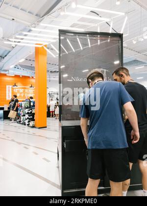 Roppenheim, Frankreich - 11. Juli 2023: Arbeiter des Nike Outlet Stores in der Nähe eines Banners - Rückansicht - Leute, die im Hintergrund einkaufen Stockfoto