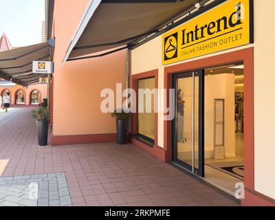 Roppenheim, Frankreich - 11. Juli 2023: Facade of Intrend Italian Fashion Outlet Door - Kunden gehen auf der Gasse im Hintergrund Einkaufsviertel Stockfoto