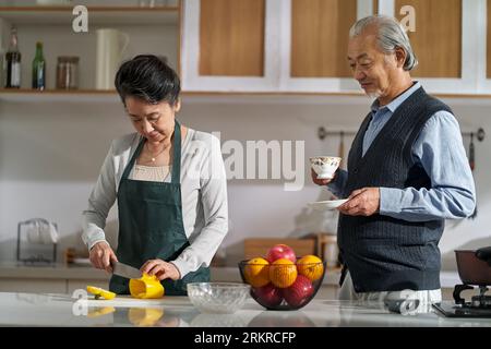 loving senior asian couple chatting talking conversing in kitchen at home while preparing food Stockfoto