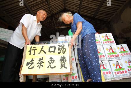 Bildnummer: 58325162  Datum: 06.08.2012  Copyright: imago/Xinhua (120808) -- NANTONG, Aug. 8, 2012 (Xinhua) -- Ding and his wife set up a poster of free tea at his store in a small village of Rugao city, of east China s Jiangsu Province, Aug. 6, 2012. An old couple running a grocery store offered free herbal tea for passers-by. Fetching well water, boiling water, preparing herbs, making tea, Ding Liangyou, the 85-year-old husband lasted the tea-offering work for 6 years, he stressed that if needed, he would carry on the good deed. (Xinhua/Huang Zhe) CHINA-JIANGSU-OLD COUPLE-FREE TEA (CN) PUBLI Stock Photo