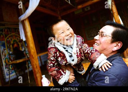 Bildnummer: 58518527 Datum: 20.09.2012 Copyright: imago/Xinhua (120926) -- TONGREN, Sept. 26, 2012 (Xinhua) -- San Tauh spielt mit seinem Enkel zu Hause im Dorf Wutun der Autonomen Präfektur Huangnan, Provinz Qinghai im Nordwesten Chinas, 20. September 2012. In den frühen Morgenstunden eines tiefen Herbstes begann der 50-jährige San Tauh sein tägliches Gebet in der Anbetungshalle zu Hause. Das Beten kostet ihn mehr als eine Stunde, einschließlich Sutras zu singen, aromatische Pflanzen anzuzünden, Kowtow und sich drehende Gebetsmühlen im nahegelegenen Tempel. Als hingebungsvoller tibetischer Buddhist verpasst San Tauh seine Anbetung während des Paus nie Stockfoto