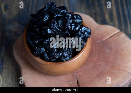 Schwarzer Pflaumenstapel aus einer großen Anzahl reifer Pflaumen, ein Pflaumenstapel auf einem Holztisch in der Küche aus nächster Nähe Stockfoto
