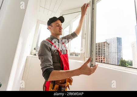 Ein junger Mechaniker repariert tagsüber den Fensterrahmen im Zimmer Stockfoto