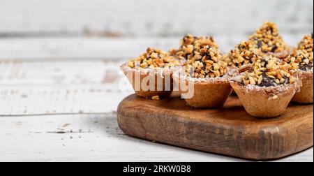 Tortenkekse. Köstliche Mini-Tartlets mit Schokoladencreme und Nüssen auf weißem Hintergrund. Leerzeichen kopieren. Leerzeichen für Text Stockfoto