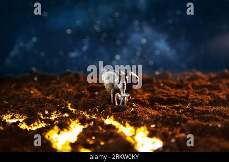 Elefant spaziert auf brennender Lava. Kreative Landschaft mit einer kleinen Miniatur. Naturkatastrophen, das Ergebnis der globalen Erwärmung. Stockfoto
