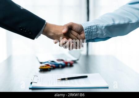 Verkaufsfrau oder Geschäftsfrau, die mit der Frau die Hand schüttelt, nachdem der Autokreditvertrag unterzeichnet wurde. Stockfoto