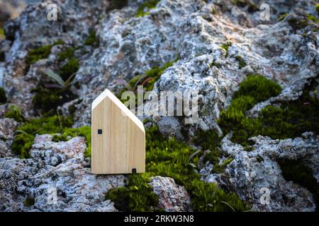 Miniatur-Haus auf Felsen oben über verschwommenem grünen Garten am Mittag Licht. Bild für Immobilien-Investitionskonzept. Bild für Liebespaar Concep Stockfoto