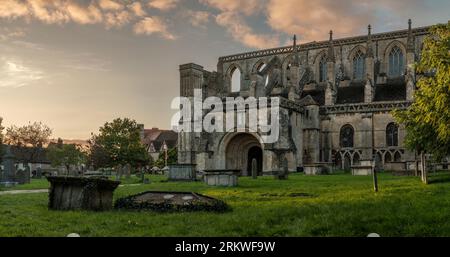 The last sunshine of the day sidelights the historic abbey at the Cotswold market town of Malmesbury. The historic abbey was founded as a Benedictine Stock Photo