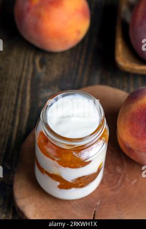 Joghurt aus frischer Milch mit süßer Pfirsichmarmelade und frischen Pfirsichen, köstlicher Joghurt mit Pfirsichgeschmack Stockfoto