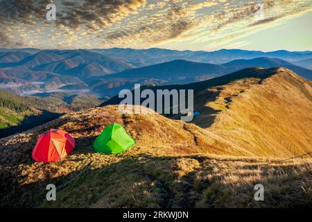 Bunte Wanderzelte auf dem Berggipfel bei Sonnenuntergang. Aktivurlaub, Wandern und Erkundungskonzept. Die Schönheit des Trekkings in den Bergen Stockfoto