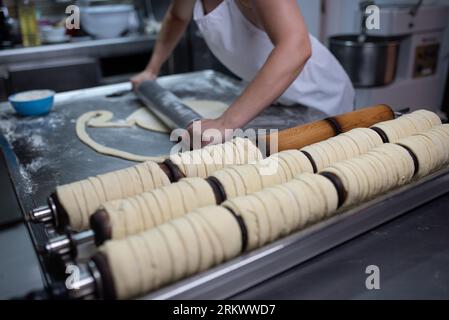 Das Mädchen rollt den Teig für ungarische Brötchen aus Stockfoto