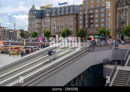Amsterdam, Niederlande - 17. Juli 2023: Man nimmt sein Fahrrad vom mehrstöckigen Fahrradparkplatz auf den Rolltreppen des Hauptbahnhofs Stockfoto