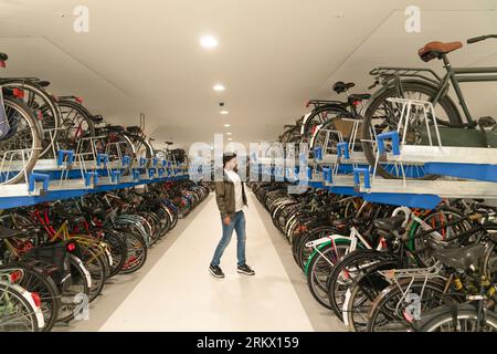 Amsterdam, Niederlande - 17. Juli 2023: Man verlässt sein Fahrrad auf einen unterirdischen, mehrstöckigen Fahrradparkplatz am Hauptbahnhof. Stockfoto