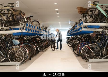 Frau nimmt ihr Fahrrad von einer mehrstöckigen Tiefgarage am Hauptbahnhof, Amsterdam, Holland Stockfoto