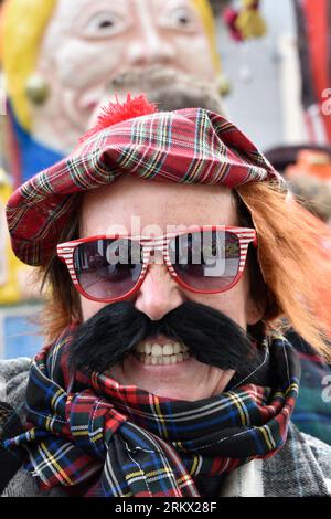 Porträt eines Karnevalsfeiernden Mannes mit Schottenkappe und Schal, dickem schwarzen Schnurrbart und rot-weißer Sonnenbrille, Breda Stockfoto