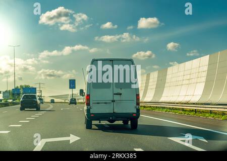 Der Van fährt bei Sonnenuntergang auf der Asphaltstraße durch den schallabsorbierenden Tunnel. Holland Stockfoto