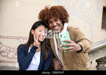 Glückliches junges Paar nimmt ein Selfie mit Telefon im Freien. Fröhliches Paar lächelt und macht draußen ein Foto. Stockfoto