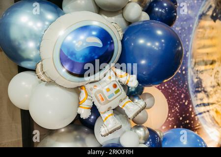 Ein astronautenförmiger Ballon vor einem Hintergrund aus blau-weißen Ballons Stockfoto