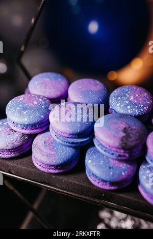 A delicious selection of intricately crafted macarons in a vibrant array of purple hues are displayed on a black tray Stock Photo