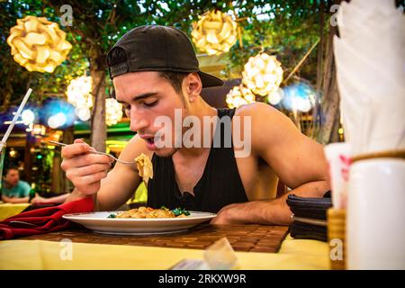 Foto eines Mannes, der eine köstliche Mahlzeit an einem Esstisch genießt Stockfoto