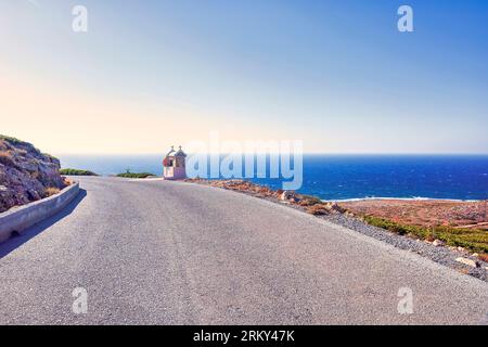 Typisch griechischer Miniatur-Schrein am Straßenrand. Kleine griechisch-orthodoxe Kapelle auf Kreta mit Meereshintergrund. Griechenland. Stockfoto