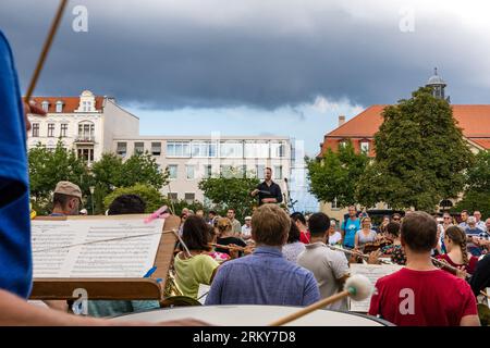 26 August 2023, Brandenburg, Cottbus: At a play-along concert on the occasion of the Cottbus State Theater's opening event for the new season, amateur musicians, conducted by General Music Director Alexander Merzyn (M), entertain the visitors in attendance. 'Together. Here.' is the motto of the Cottbus State Theater for the 2023/24 season, which the Brandenburg four-speaker theater is celebrating this weekend together with citizens. A total of 19 premieres in the drama, musical theater and ballet divisions, eight philharmonic concerts and numerous events in the 'Special Format' and 'Special' s Stock Photo