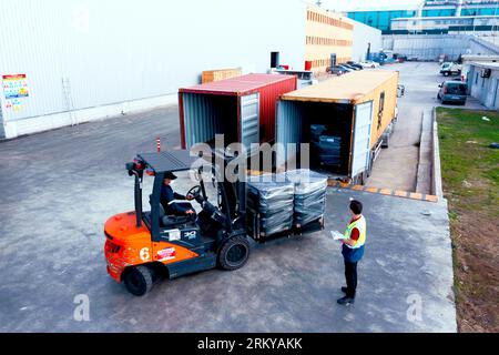 Der Gabelstapler transportiert Fracht von Lager zu Lkw. Gabelstapler im Freien. Arbeiter beladen Palette mit einem Gabelstapler in einen Stapler. Stockfoto