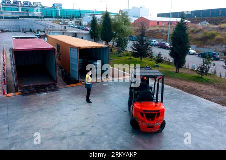 Der Gabelstapler transportiert Fracht von Lager zu Lkw. Gabelstapler im Freien. Arbeiter beladen Palette mit einem Gabelstapler in einen Stapler. Stockfoto