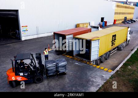 Der Gabelstapler transportiert Fracht von Lager zu Lkw. Gabelstapler im Freien. Arbeiter beladen Palette mit einem Gabelstapler in einen Stapler. Stockfoto