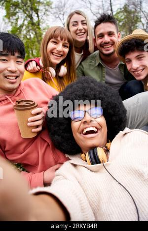 Vertikales glückliches Selfie von jungen Freunden aus mehreren ethnischen Gruppen, die vor der Kamera lachen. Porträt Gen z Stockfoto