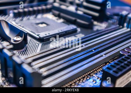 Modernes PC-Mainboard mit AM4-CPU-Sockel. Die Komponenten des Computerhardware-Chipsatzes werden in blauem Licht näher betrachtet. Hintergrund der Elektronik in der Technologiebranche Stockfoto