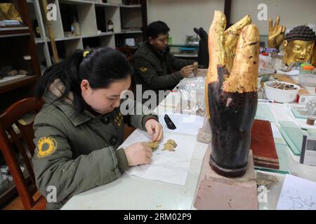 Bildnummer: 59309210 Datum: 04.03.2013 Copyright: imago/Xinhua CHONGQING -- Yang Honglan, das jüngste Mitglied des Restaurierungsteams der Steinskulptur von Guanyin (Avalokitesvara) Bodhisattva mit tausend Händen, beschäftigt sich mit Goldfolie bei Dazu Rock Carvings im Dazu County, etwa 165 Kilometer westlich der Gemeinde Chongqing im Südwesten Chinas, am 4. März 2013. Die Skulptur von Qianshou Guanyin, der Bodhisattva mit tausend Händen, die von ostasiatischen Buddhisten verehrt werden, wurde vor etwa 800 Jahren während der südlichen Song-Dynastie (1127 bis 1279) geschnitzt. Der Restaurierungsprofis Stockfoto