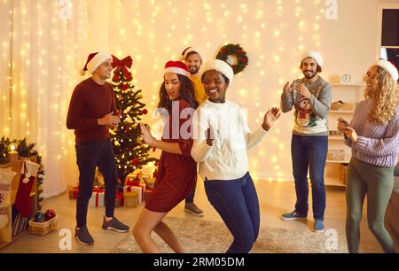 Überschwängliche, multirassische Freunde tanzen auf der Weihnachtsfeier Stockfoto