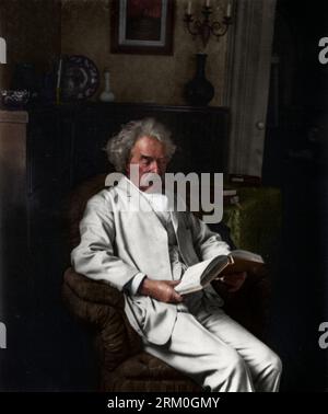 Porträt von Samuel Clemens, „Mark Twain“, der auf einem Stuhl sitzt und ein Buch liest. Ca. 1907. Fotograf: Underwood & Underwood. Hinweis: Der Fotorahmen auf dem W Stockfoto