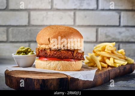 Schließen Sie köstliche frische Burger und Pommes Frites auf Holzbrett. Und Backsteinhintergrund. Isoliertes Bild eines schönen Hamburger Stockfoto